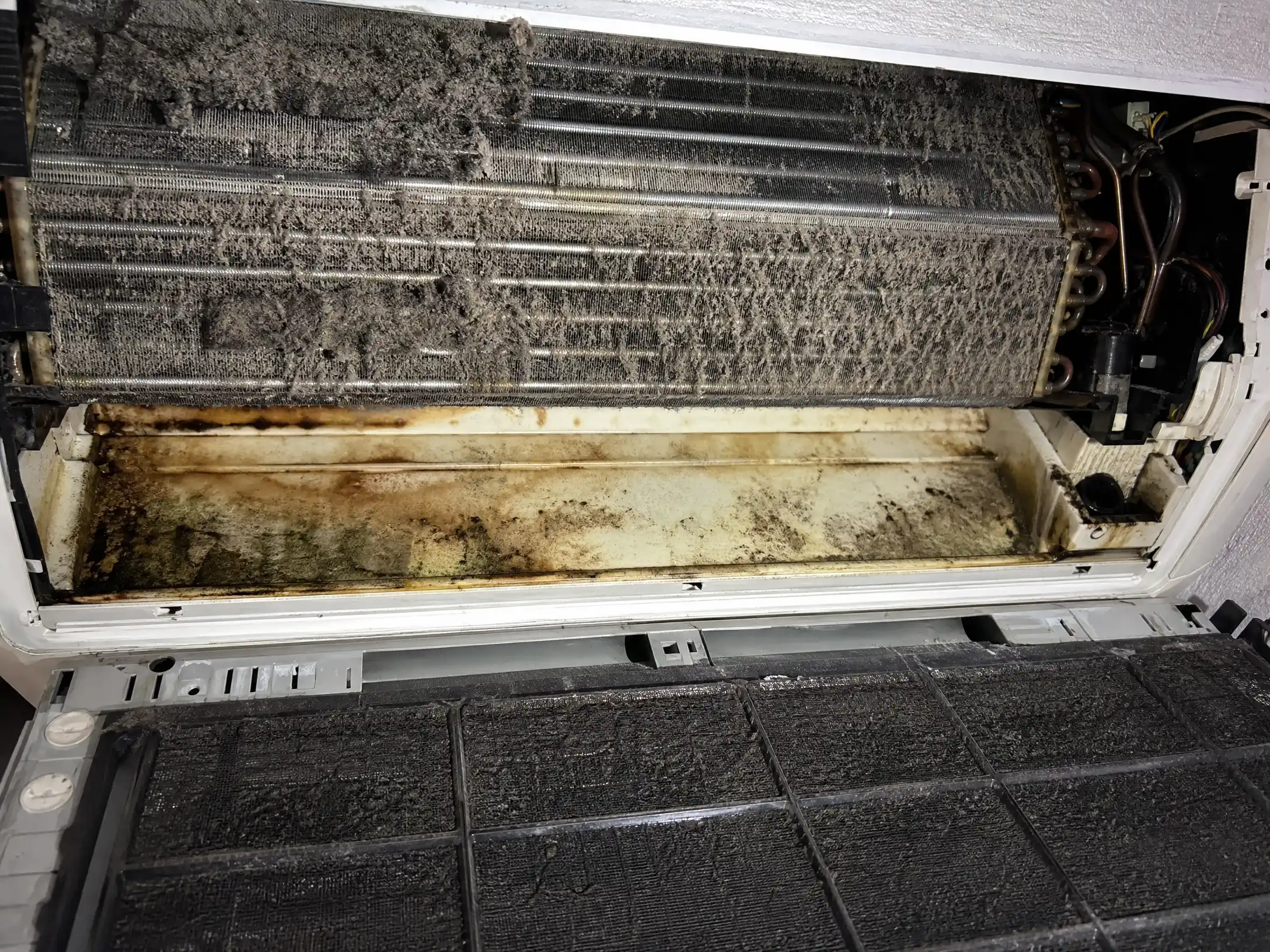 Fan-coil výměník před čištěním — zanesené lamely, kondenzátní vana